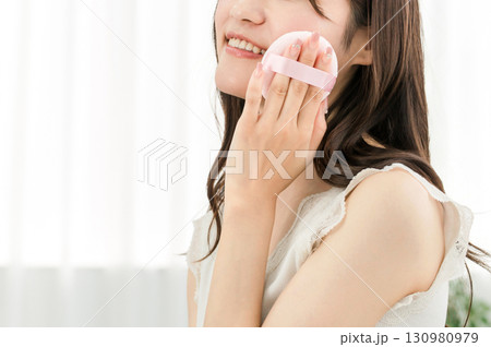 ファンデーション・パウダー・メイクする笑顔のアジア人女性 130980979
