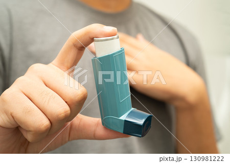 Asthma and chronic obstructive pulmonary disease COPD, Asian young man using metered dose inhaler MDI. 130981222