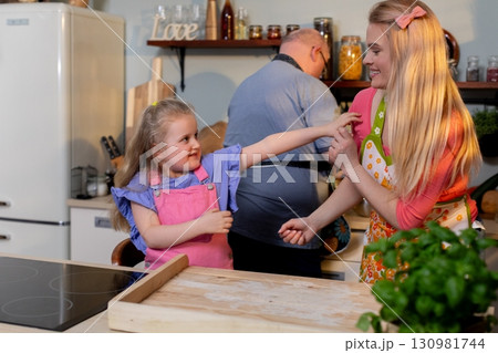 A Joyful Family Cooking Together in Their Warm and Inviting Home Kitchen, Creating Memories 130981744