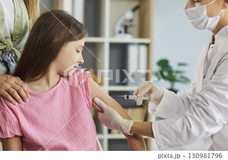 Pediatric clinic vaccination: doctor gives child an injection while parent helps 130981796