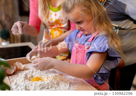 A Child is Joyfully Enjoying Baking Together with Adults in a Cozy and Inviting Kitchen Space A Child is Joyfully Enjoying Baking Together with Adults in a Cozy and Inviting Kitchen Space 130982206