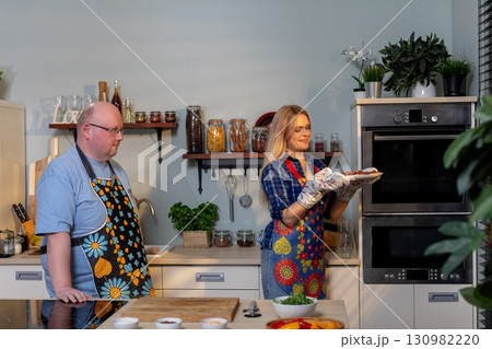 A cheerful cooking duo in colorful aprons joyfully prepares a delicious meal together 130982220