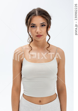 Trendy Young Woman Showcasing a Stylish and Fashionable Outfit Set Against a White Background Trendy Young Woman Showcasing a Stylish and Fashionable Outfit Set Against a White Background 130982226