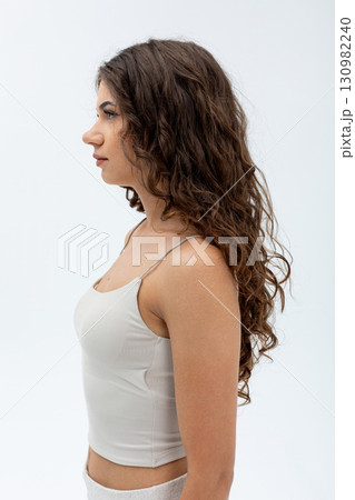 Here is a portrait profile of a beautiful woman showcasing her long, curly hair gracefully Here is a portrait profile of a beautiful woman showcasing her long, curly hair gracefully 130982240