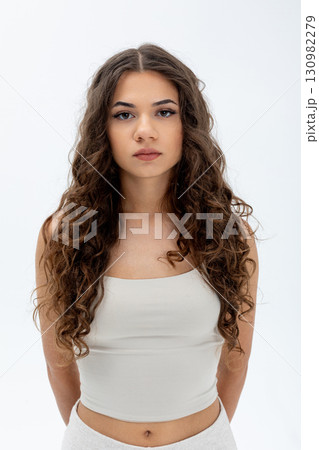 A Young Woman Exuding Confidence, Sporting Beautifully Curly Hair While Posing in a Studio Setting 130982279