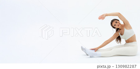 A woman in white athleisure stretches in a minimalist background, embodying calm and wellness A woman in white athleisure stretches in a minimalist background, embodying calm and wellness 130982287