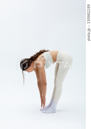 A Woman Engaged in Practicing Yoga Through the Forward Bend Posture for Better Wellness 130982289