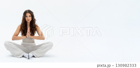 A Serene Meditation Pose featuring a Focused Young Woman in a Calm and Peaceful Setting A Serene Meditation Pose featuring a Focused Young Woman in a Calm and Peaceful Setting 130982333
