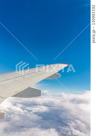 View from the airplane window at a beautiful cloudy sky and the airplane wing View from the airplane window at a beautiful cloudy sky and the airplane wing 130983192