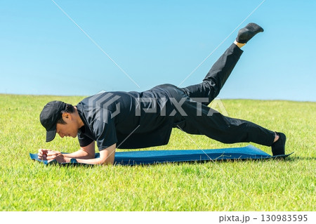 公園でヨガ・ピラティスをする男性(運動・ワークアウト・ヨガ・スポーツ・ストレッチ) 130983595