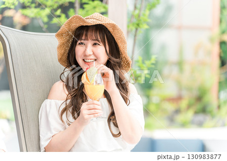 プールサイドのリクライニングチェアに座りトロピカルジュースを飲む若いアジア人女性 プールサイドのリクライニングチェアに座りトロピカルジュースを飲む若いアジア人女性 130983877