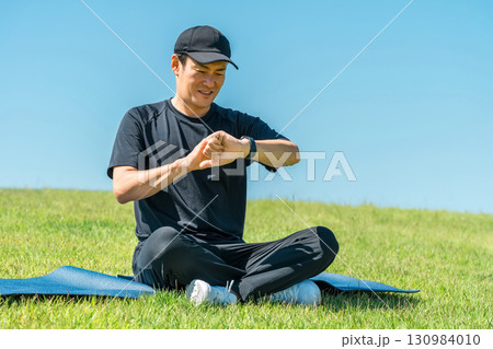 スマートウォッチ,スマートバンドを使ってヨガ,ストレッチ,ヘルスケアをするスポーツウェア姿の中年男性 スマートウォッチ,スマートバンドを使ってヨガ,ストレッチ,ヘルスケアをするスポーツウェア姿の中年男性 130984010