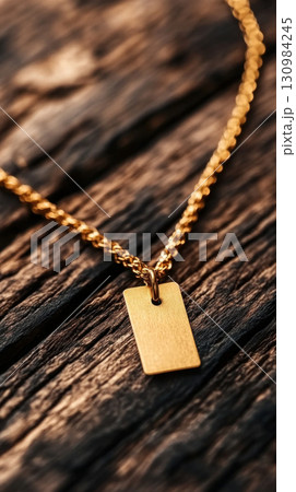 Close-up of a stylish gold necklace featuring a blank tag on a rustic wooden background, perfect for jewelry or fashion themes. 130984245