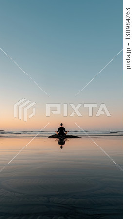 Relaxing meditation session on a beach at sunset, soft light, wideangle lens, natural colors, serene setting 130984763