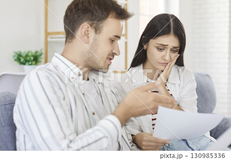 Serious stressed young couple at home worried about paper document, discussing budget, unpaid debt 130985336