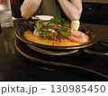 パエリアを食べる女性 130985450