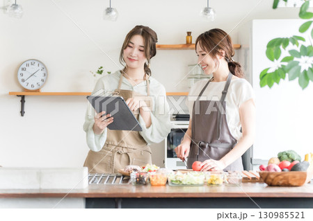 料理教室・クッキングスクールで料理を教える講師の女性と生徒の女性 130985521