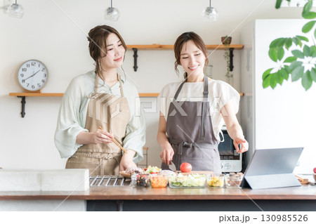 タブレットを見ながらキッチンで料理をする女性（オンライン料理教室,配信） 130985526