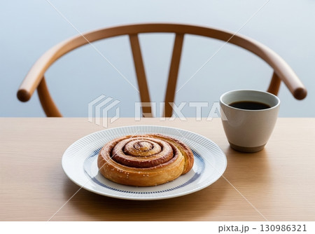 Danish kanelsnegl cinnamon roll with a cup of coffee on a table for a traditional fika Danish kanelsnegl cinnamon roll with a cup of coffee on a table for a traditional fika 130986321