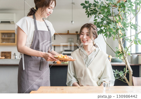 カフェでワンプレートランチを提供,配膳する店員と女性客 カフェでワンプレートランチを提供,配膳する店員と女性客 130986442