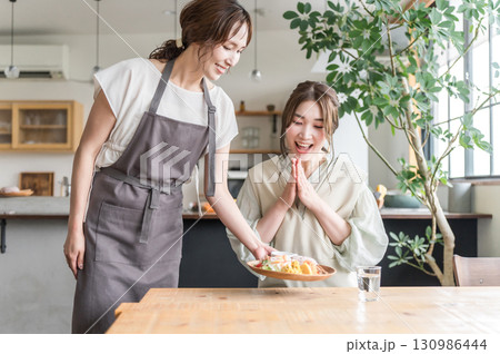 カフェでワンプレートランチを提供,配膳する店員と女性客 カフェでワンプレートランチを提供,配膳する店員と女性客 130986444