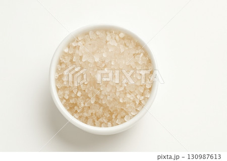 Coarse sea salt crystals in white bowl on white background 130987613