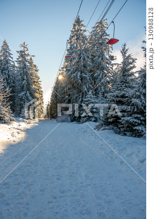 Snow covered forest in Sumava with trees wrapped in white snow and deep snowdrifts, illuminated by the warm colors of the setting sun, creating a calm winter landscape. Snow covered forest in Sumava with trees wrapped in white snow and deep snowdrifts, illuminated by the warm colors of the setting sun, creating a calm winter landscape. 130988128