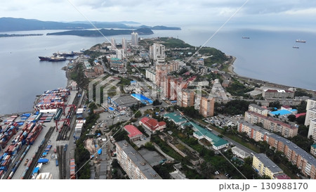 Aerial view of a port city with cargo ships navigating the bay, showcasing urban infrastructure and maritime activity 130988170