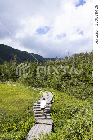 木道をハイキングする男性 130989426