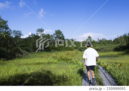 木道をハイキングする男性 130990091