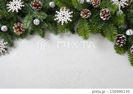 Christmas frame with evergreen branches and carving wooden eco natural decorations, snowflakes, pine cones on white background. Copy space. Xmas greeting card. Winter Holiday. View from above. 130990130