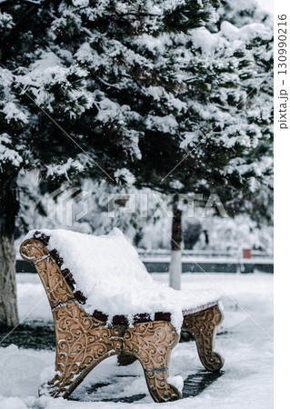 Snowy bench in winter park. 130990216