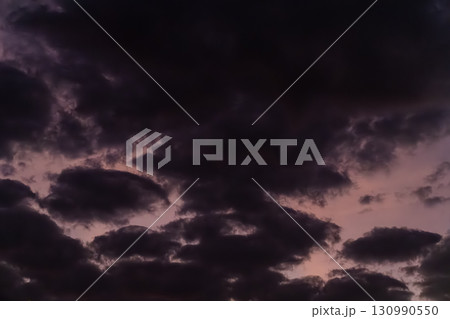 Thick dark clouds cover the sky during twilight as the last traces of light fade. The scene feels heavy and quiet as night approaches. Thick dark clouds cover the sky during twilight as the last traces of light fade. The scene feels heavy and quiet as night approaches. 130990550