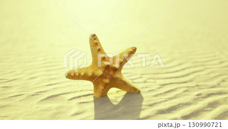 A solitary golden starfish lies on the smooth, sunlit sand of a peaceful beach. Gentle waves ripple in the background, creating a serene atmosphere at twilight. 130990721