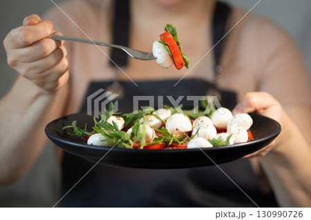 Chef Carefully Serves a Fresh Salad With Mozzarella, Tomatoes, and Arugula for a Healthy Meal Chef Carefully Serves a Fresh Salad With Mozzarella, Tomatoes, and Arugula for a Healthy Meal 130990726