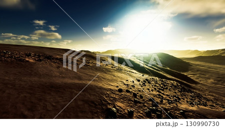 Sunrise casts a warm glow over a serene desert terrain, highlighting winding hills and scattered rocks, evoking a sense of peace and the beauty of natures solitude. 130990730