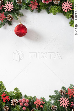 Christmas frame with red bauble and evergreen branches pine cones on white background. Copy space. Xmas greeting card. Winter Holiday card. Top view Christmas frame with red bauble and evergreen branches pine cones on white background. Copy space. Xmas greeting card. Winter Holiday card. Top view 130990837