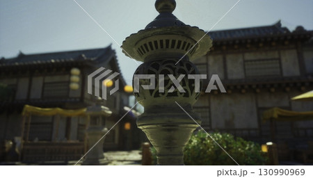 Beautiful traditional structures in Japan feature intricate architecture and beautiful lanterns. The sunlight adds a warm touch to the serene garden atmosphere. 130990969