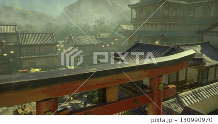 A serene Japanese village sits nestled among misty mountains during dusk. Traditional wooden homes with tiled roofs and lanterns illuminate the surroundings, creating a peaceful atmosphere. 130990970