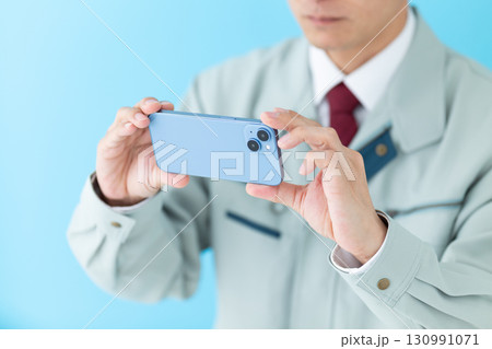 スマホで撮影をする作業着姿のミドル男性ビジネスマン 130991071