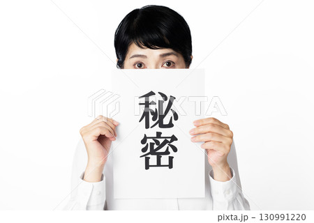 秘密と書かれた紙の後ろから凝視するシニア女性 秘密と書かれた紙の後ろから凝視するシニア女性 130991220