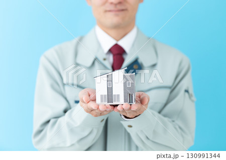 住宅模型を持つ作業着姿のミドル男性ビジネスマン 130991344