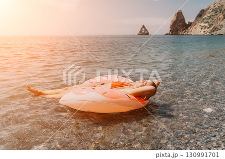 Woman, Inflatable Ring, Sea - Relaxing on Inflatable Ring in the Sea at Sunset 130991701