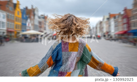 Fashion influencer twirls in vibrant patchwork clothes on a lively street 130992025