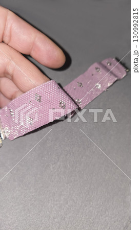 A pink Japanese handmade beaded bracelet on a light background. Embellishments. A pink Japanese handmade beaded bracelet on a light background. Embellishments. 130992815