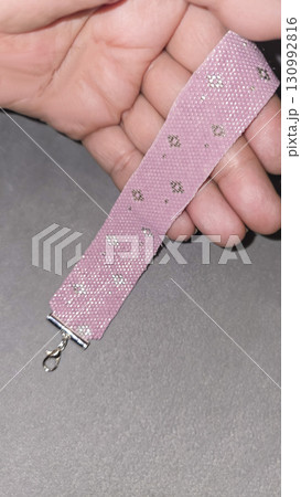 A pink Japanese handmade beaded bracelet on a light background. Embellishments. 130992816