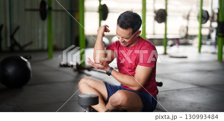 Fitness Injury. Young man feeling elbow pain during weight training in gym. Fitness Injury. Young man feeling elbow pain during weight training in gym. 130993484