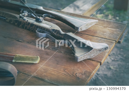 old shotgun with wooden barrel and iron butt on wooden table toned background 130994370