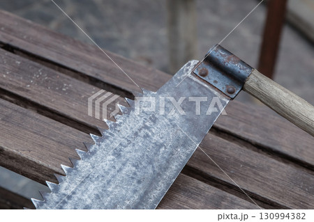 and saw close-up against the background of boards, a saw with large teeth and saw close-up against the background of boards, a saw with large teeth 130994382