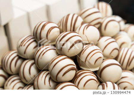 sweets covered with white chocolate and brown lines close-up sweets covered with white chocolate and brown lines close-up 130994474